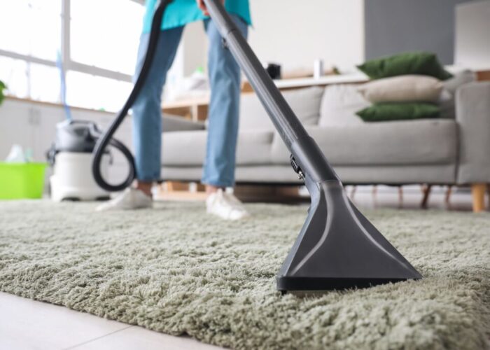 Young man hoovering carpet at home, closeup