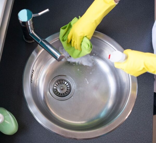 Hands in yellow rubber gloves washing the sink Hands in yellow rubber gloves washing the sink