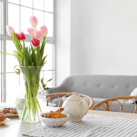 Vase with beautiful tulip flowers on dining table in room